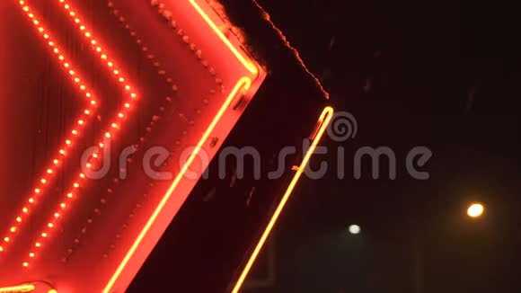 雪片在夜晚落在红色的霓虹灯中发光的箭头通向加油站视频的预览图