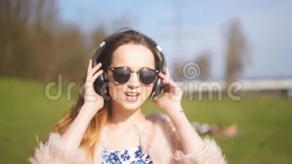 穿着蓝牙耳机的女孩在外面唱歌跳舞一个留着长发戴着墨镜在公园跳舞流汗的可爱女孩视频的预览图