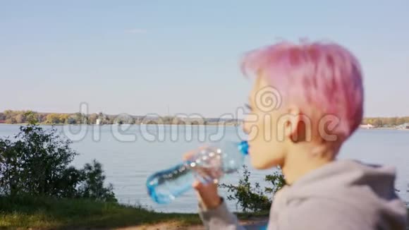 粉红头发的年轻女士在湖边慢跑视频的预览图