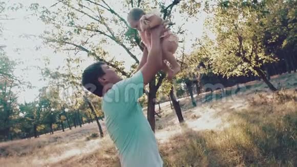 父亲把他的孩子扔到秋天公园的空中透过爸爸肩膀看视频的预览图