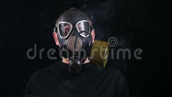一个戴着防毒面具的人的脸在黑色的背景下可以抵御烟雾视频的预览图