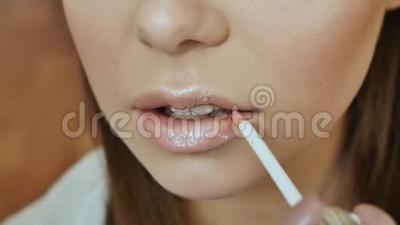 女孩化妆师用柔和的粉红色画女孩嘴唇模型视频的预览图