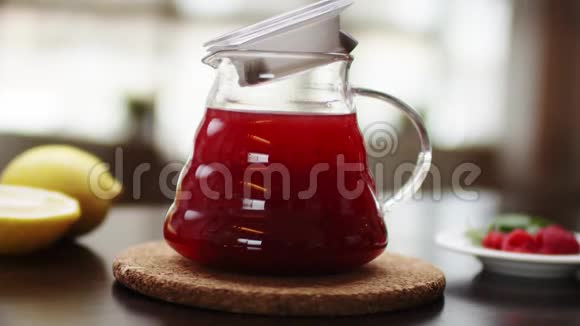 特写一个有热水和花红茶的茶壶动作慢一只手正在木器上用茶壶装饰茶视频的预览图