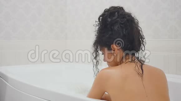 坐在浴缸里洗澡的年轻女人慢动作视频的预览图