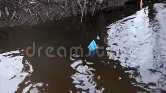 彩纸的蓝色纸船沿着秋天的小溪漂浮视频的预览图
