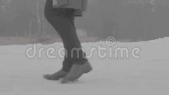 穿着灰色斗篷穿着黑色牛仔裤穿着灰色靴子的人蒙的冬日踏雪视频的预览图