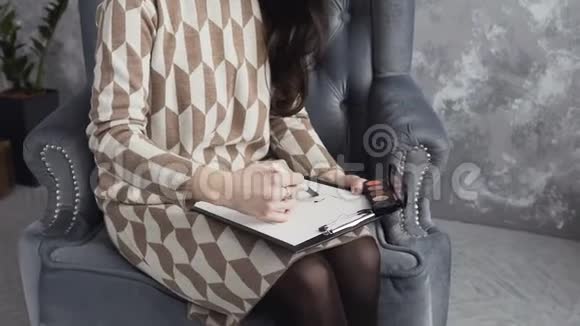 脸图美丽的黑发女人坐在家里柔软的扶手椅上用画笔绘制一张脸图视频的预览图