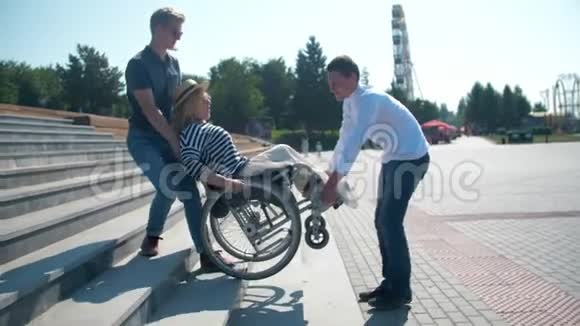 两个男人在台阶上抱着一个坐轮椅的女人视频的预览图