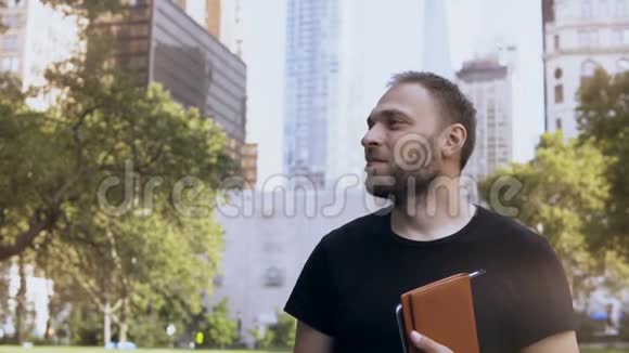 年轻的快乐商人拿着文件站在公园里靠近美国纽约的金融区视频的预览图