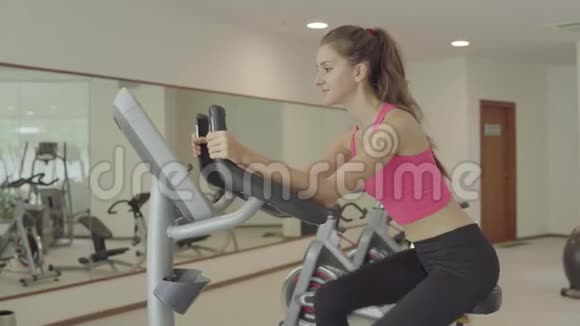 在健身房骑运动自行车的女人骑自行车运动的女性视频的预览图