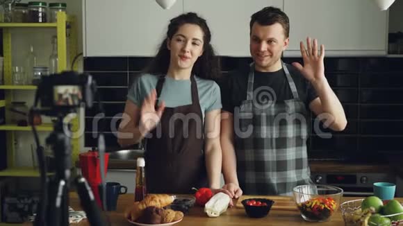 在家的厨房里用数码相机拍摄一对迷人的情侣录下有关烹饪美味沙拉的视频食物视频的预览图