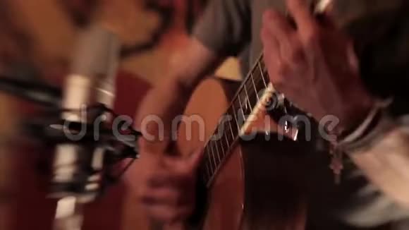 职业男性吉他手正在麦克风前的红色工作室里演奏吉他视频的预览图