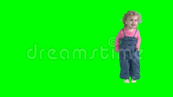 活泼的幼儿女孩在绿色背景下跳跃和移动视频的预览图