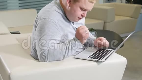 办公室工作理念一个人坐在舒适的白色沙发上在笔记本电脑旁浏览着视频的预览图
