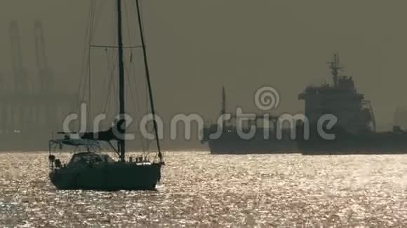 直布罗陀附近一艘不知名的帆船和大型货船的剪影视频的预览图