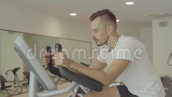 一个人在健身房骑自行车锻炼他的腿做有氧训练骑自行车视频的预览图