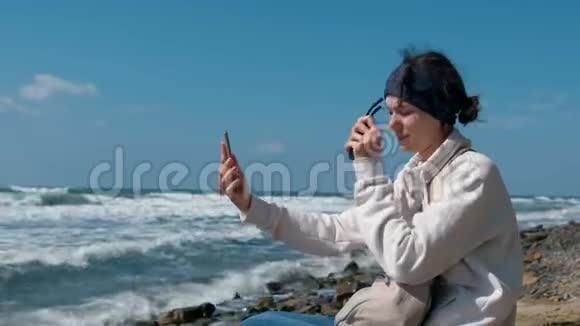 秋天女人在石滩上坐在海边自拍视频的预览图