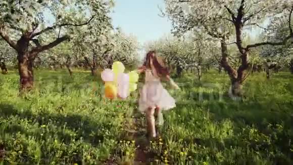 快乐的女孩带着气球在盛开的花园里奔跑视频的预览图