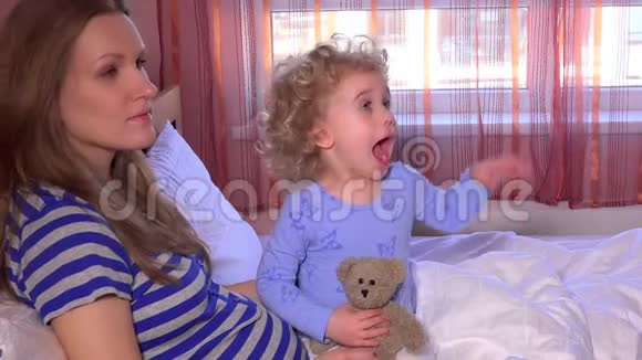 生病的孩子妈妈张开嘴从坐在床上的男医生那里吃药视频的预览图