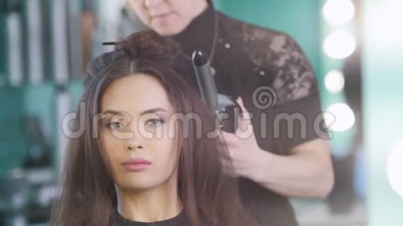 发型大师为有魅力的女模特打造晚间发型视频的预览图