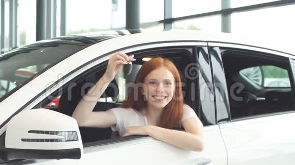 司机女士喜出望外坐在汽车陈列室时微笑着展示新钥匙视频的预览图
