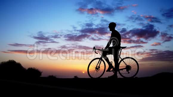 日落时分在岩石上骑自行车的剪影视频的预览图