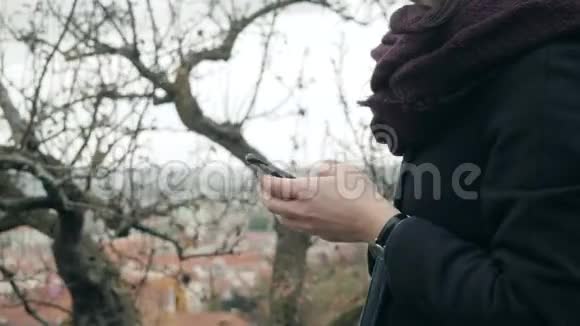 在公园里用智能手机坐在长凳上合上女人的手美丽的欧洲女孩打电话发短信视频的预览图