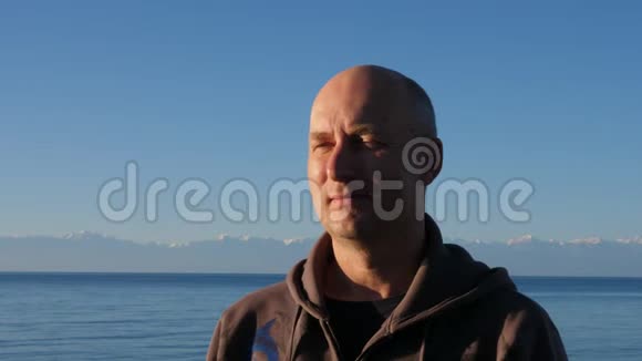 在山顶和蓝色湖IssykKul景观中描绘成年男子视频的预览图