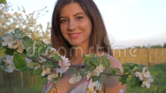 一位年轻的高加索女人站在一个盛开的苹果园里的肖像视频的预览图