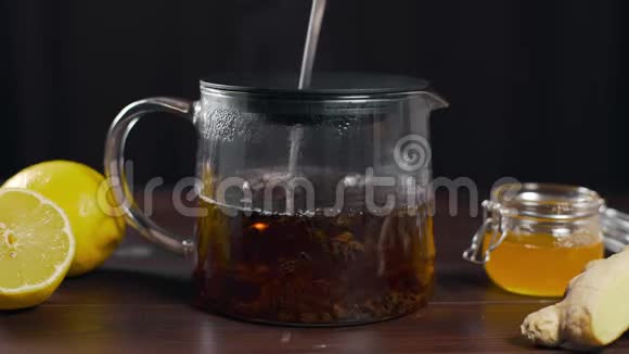沏好的红茶用长勺在玻璃茶壶里搅拌维生素茶用柠檬生姜和蜂蜜搅拌饮用视频的预览图