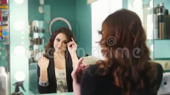 一位年轻的黑发女郎在美容院欣赏镜子里的倒影视频的预览图