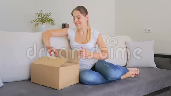 快乐美丽的女人把她在网上订购的衣服从盒子里拿出来视频的预览图
