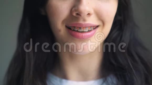 一个戴牙套的年轻女孩歪着头出现在框架里白色墙底的年轻女子视频的预览图