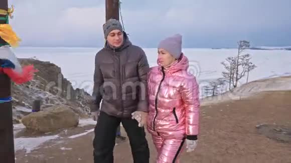 年轻夫妇喜欢在冬天的山顶上散步冬天用彩带做的佛教仪式柱视频的预览图