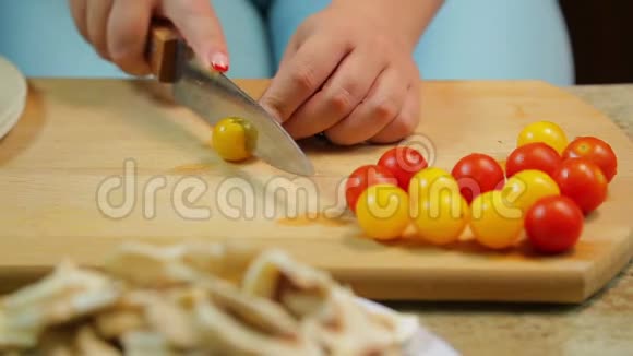 一个女人正在用一把刀切一个黄色和红色的樱桃番茄视频的预览图