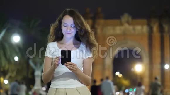 巴塞罗那晚上快乐的女人在智能手机上发短信视频的预览图