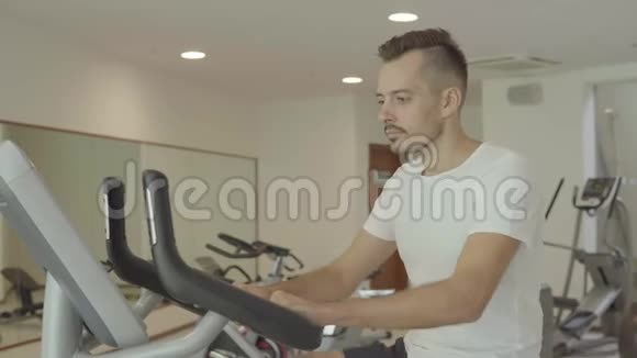 男子骑自行车在健身房锻炼他的腿做有氧训练骑自行车视频的预览图