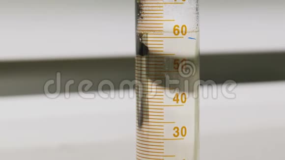 油倒在量杯中漂浮在实验室的透明液体上视频的预览图