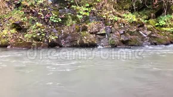 大石头掉进快速流动的山河产生大量的飞溅气泡波浪和水滴视频的预览图