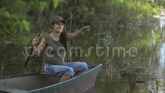 年轻女子渔夫正在森林湖上钓鱼拿着鱼竿扭动着线圈视频的预览图