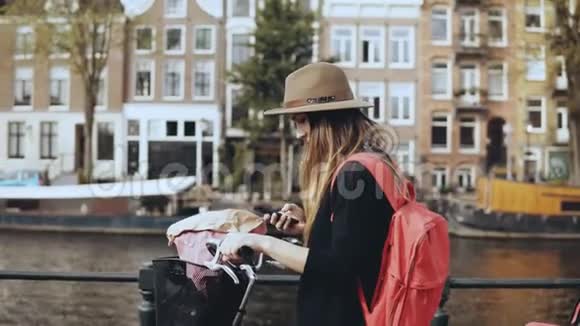 可爱的女士骑自行车在智能手机上拍照年轻的高加索女记者令人惊叹的古镇建筑4K视频的预览图
