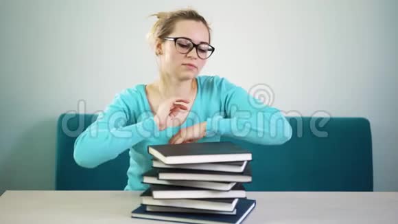一个戴着眼镜睡在图书馆书上的疲惫的学生女孩视频的预览图