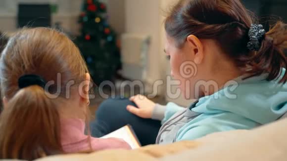 妈妈带着小女儿玩得很开心在家里的沙发上一起读这本书10岁的女孩和她妈妈视频的预览图