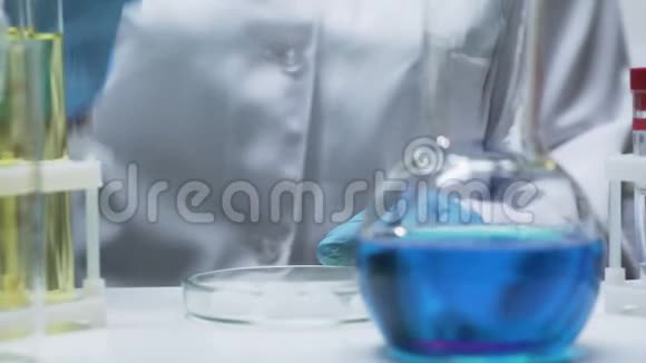 实验室助理将干冰加入明亮的蓝色混合物中导致气泡视频的预览图
