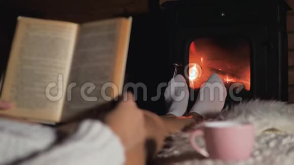 女人躺在壁炉前的软地毯上看书视频的预览图