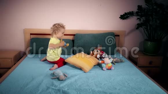 淘气的孩子在卧室里把玩具扔到床上视频的预览图