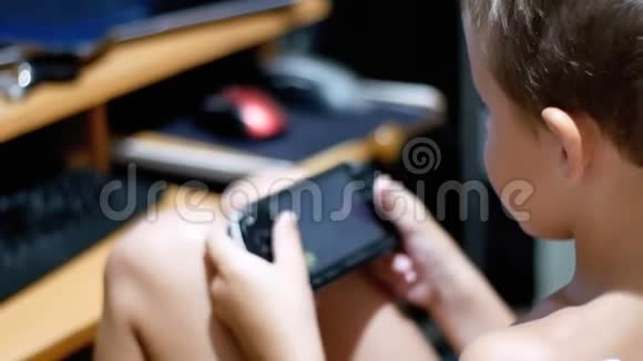 8岁的孩子在家里坐在椅子上的便携式游戏机上玩电子游戏视频的预览图