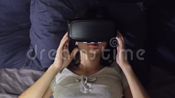 躺在床上枕头上的年轻女性的俯视图使用虚拟现实视频的预览图
