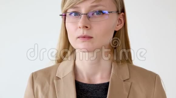 一位戴眼镜的严肃商务女性的肖像和一件白色背景的夹克特写视频的预览图