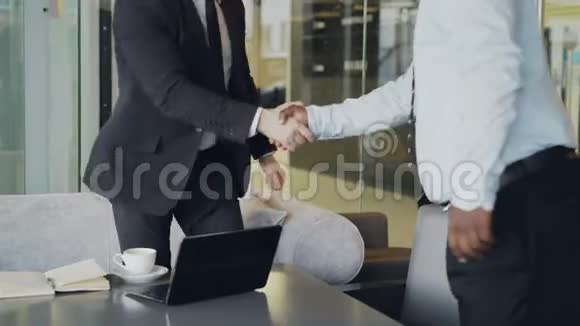 两位穿着正式服装的商人握手坐在白色的扶手椅上讨论他们的创业视频的预览图